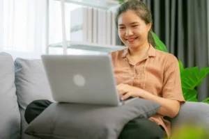 Woman sitting on couch using laptop